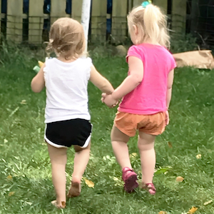 Two girls walking together holding hands outdoors